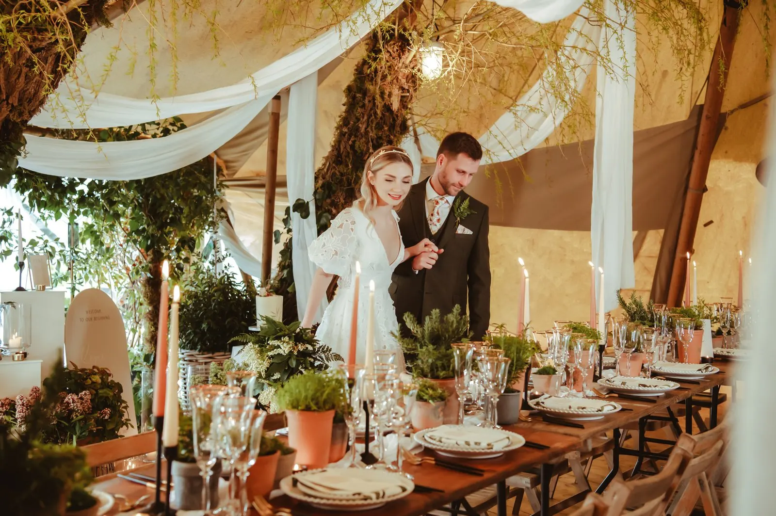 Bride and groom beside a candlelit banquet table inside the Garden Tipi
